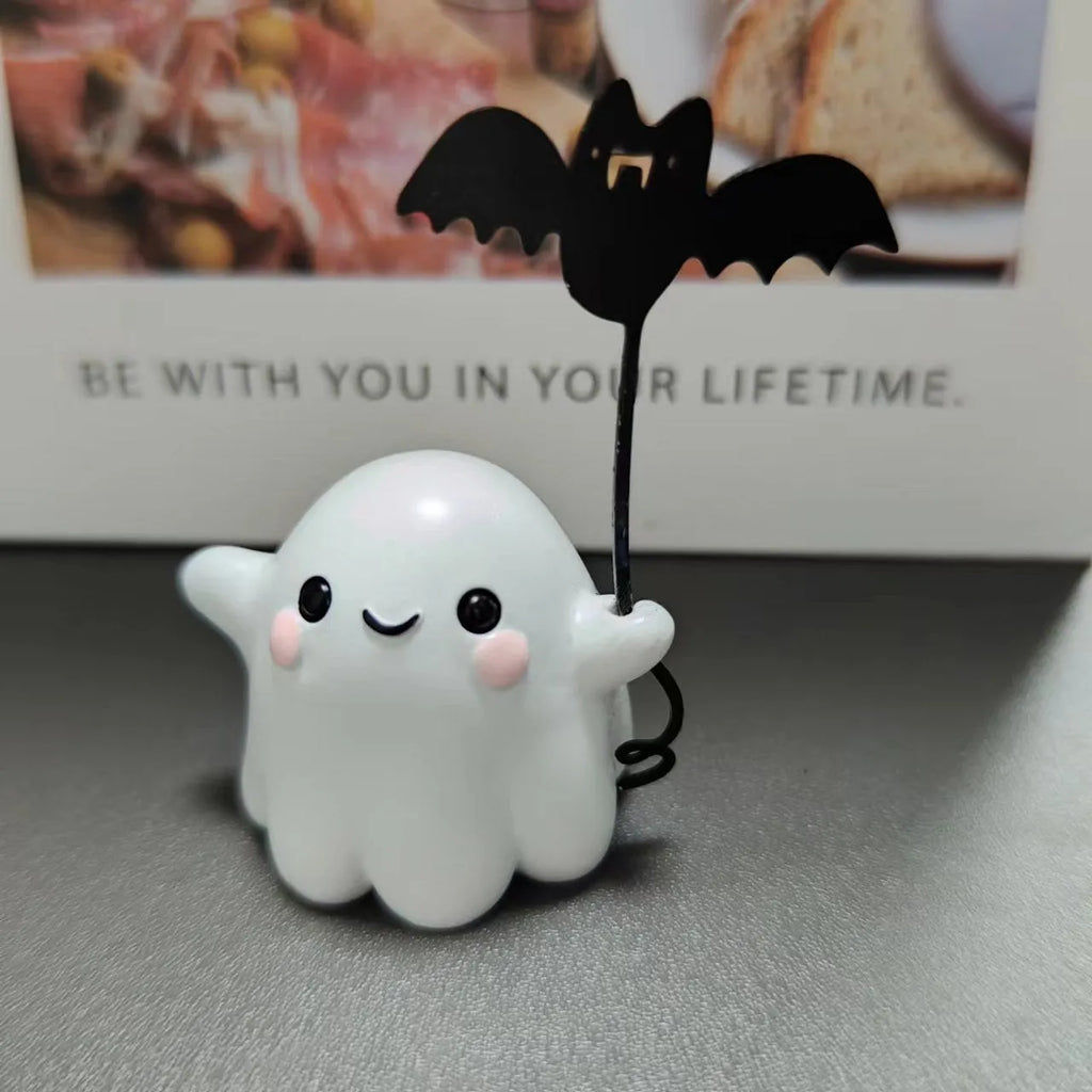 Mini resin Halloween statue of a white ghost dog walking and holding a small black bat.