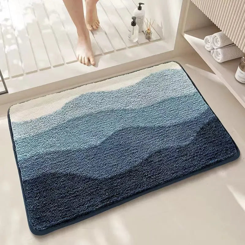 Square rainbow print floor mat with blue tones and a plastic anti-slip backing on a wooden floor.