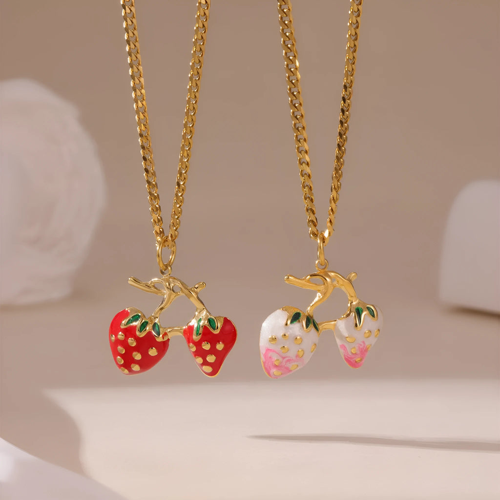 Close-up of a strawberry-shaped alloy pendant necklace on a stainless steel chain, showing red and white colour options.