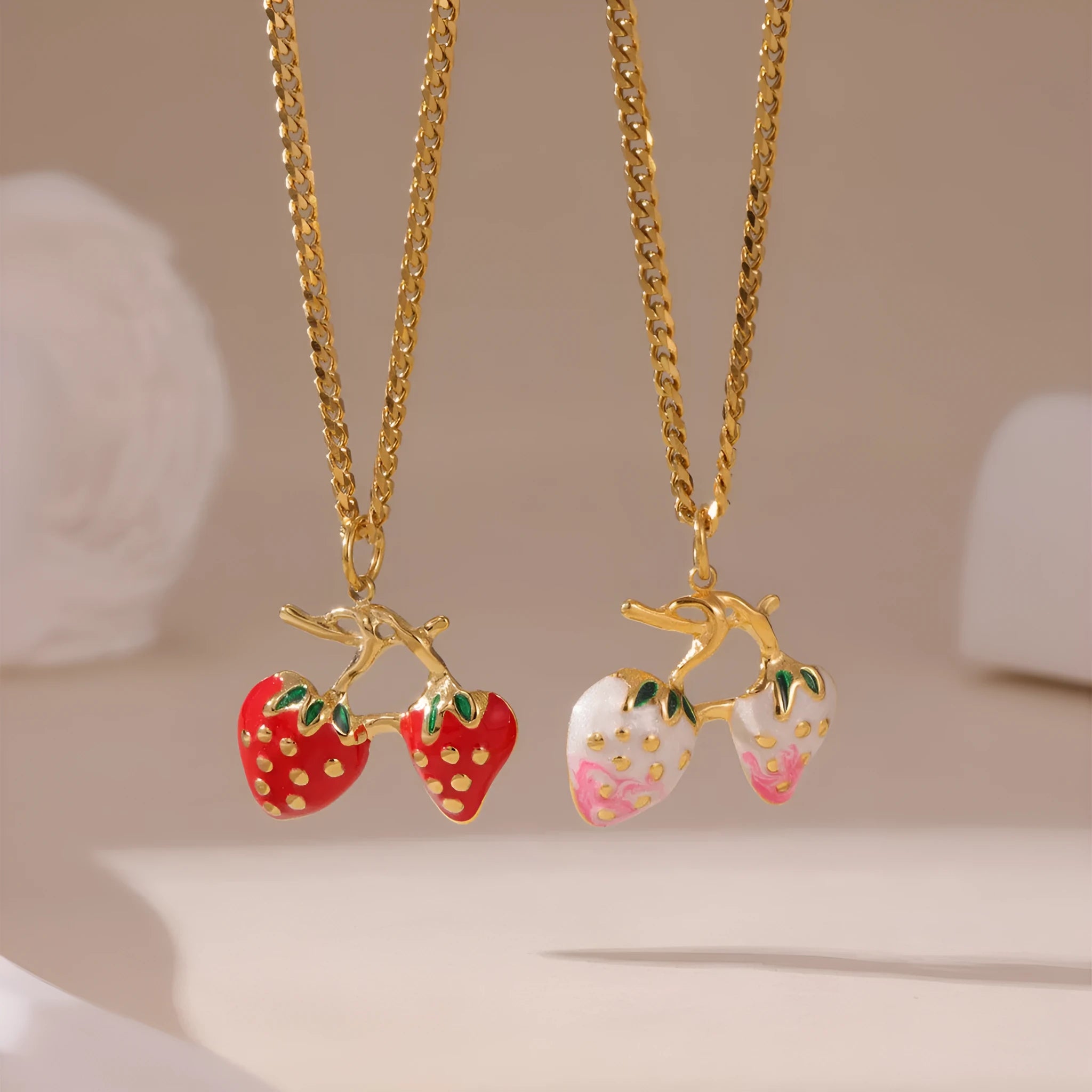 Close-up of a strawberry-shaped alloy pendant necklace on a stainless steel chain, showing red and white colour options.