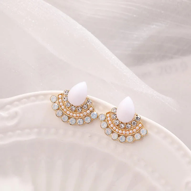 Close-up of a pair of women's retro fan-shaped silver earrings with rhinestone details on a geometric alloy setting.