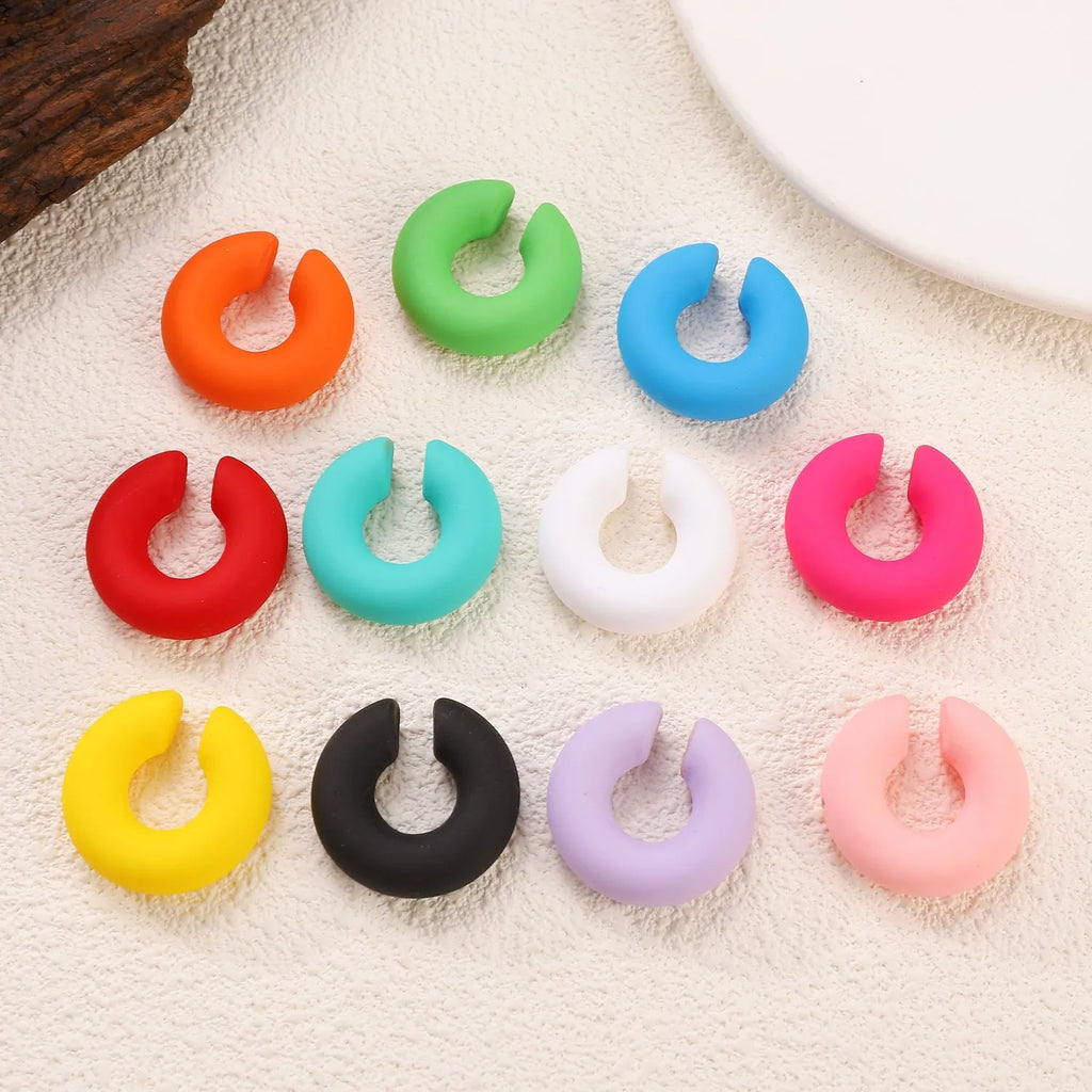 Close-up of matte finish, coarse round C-shaped clip-on earrings for women in a candy colour.