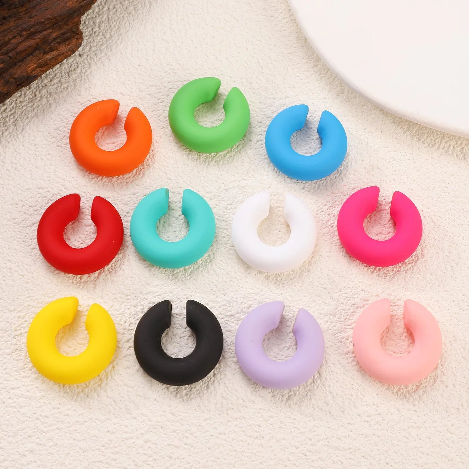 Close-up of matte finish, coarse round C-shaped clip-on earrings for women in a candy colour.