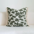 Green striped and botanical patterned pillow with beaded fringe on a bed.