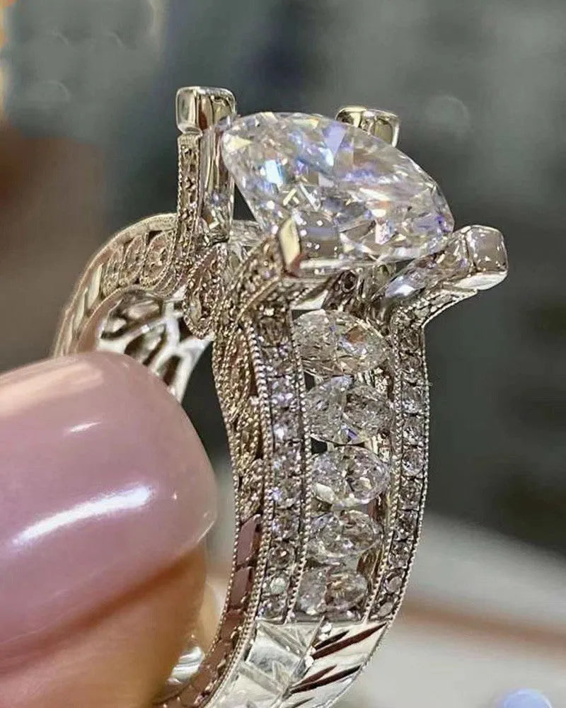 A geometric silver-tone women's ring with a round design element on a model's hand.