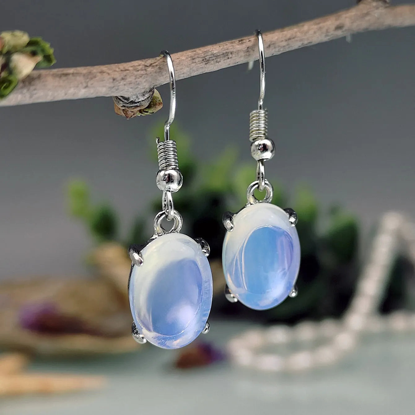 A pair of retro drop-shaped alloy earrings with electroplated moonstone opal colour and ellipse design elements.