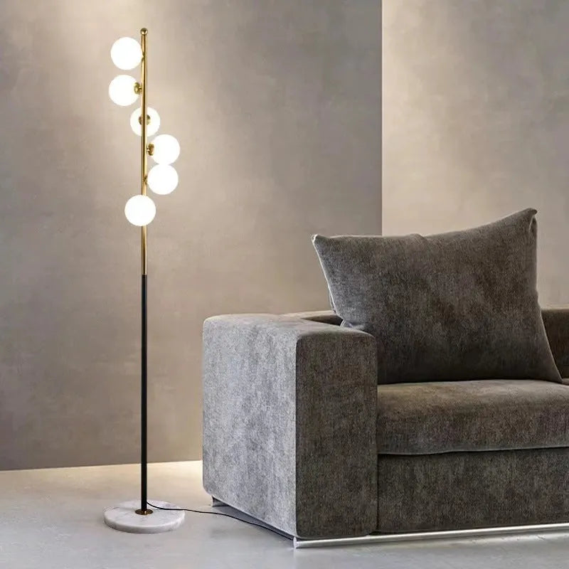 A tall, minimalist Nordic-style floor lamp with a wrought iron frame, glass details, and a circular marble base.