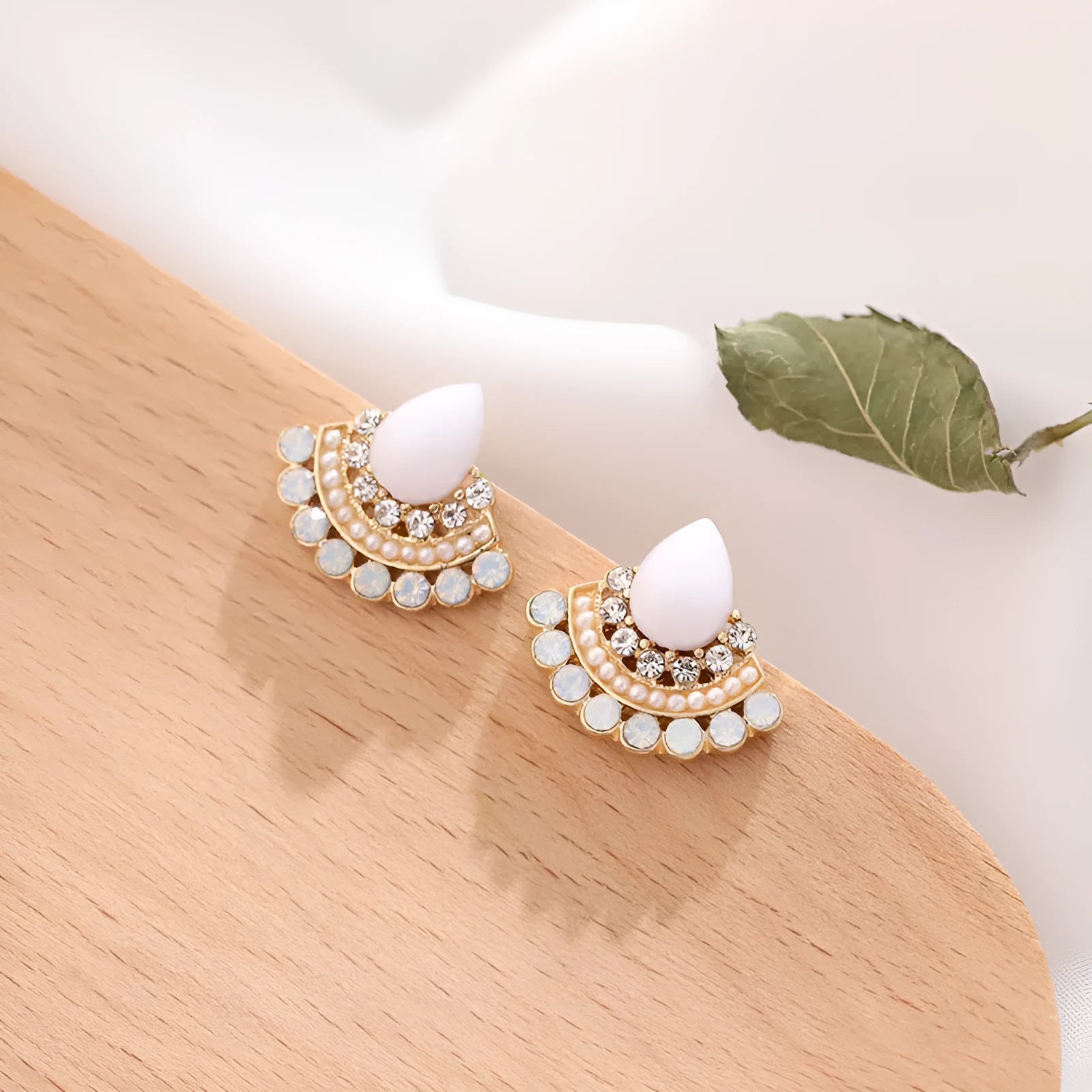 Close-up of a pair of women's retro fan-shaped silver earrings with rhinestone details on a geometric alloy setting.