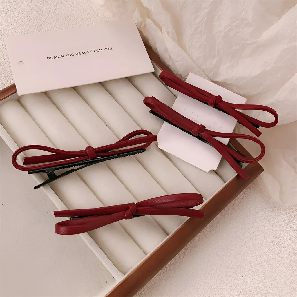 Wine red genuine leather bow hair barrette with a silver metal pinch clip on a white background.