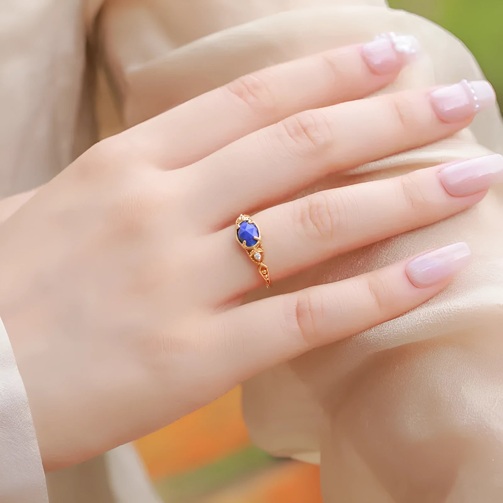 A geometric silver-tone alloy ring in a lapis lazuli colour, showing its elliptical profile and rounded elements.