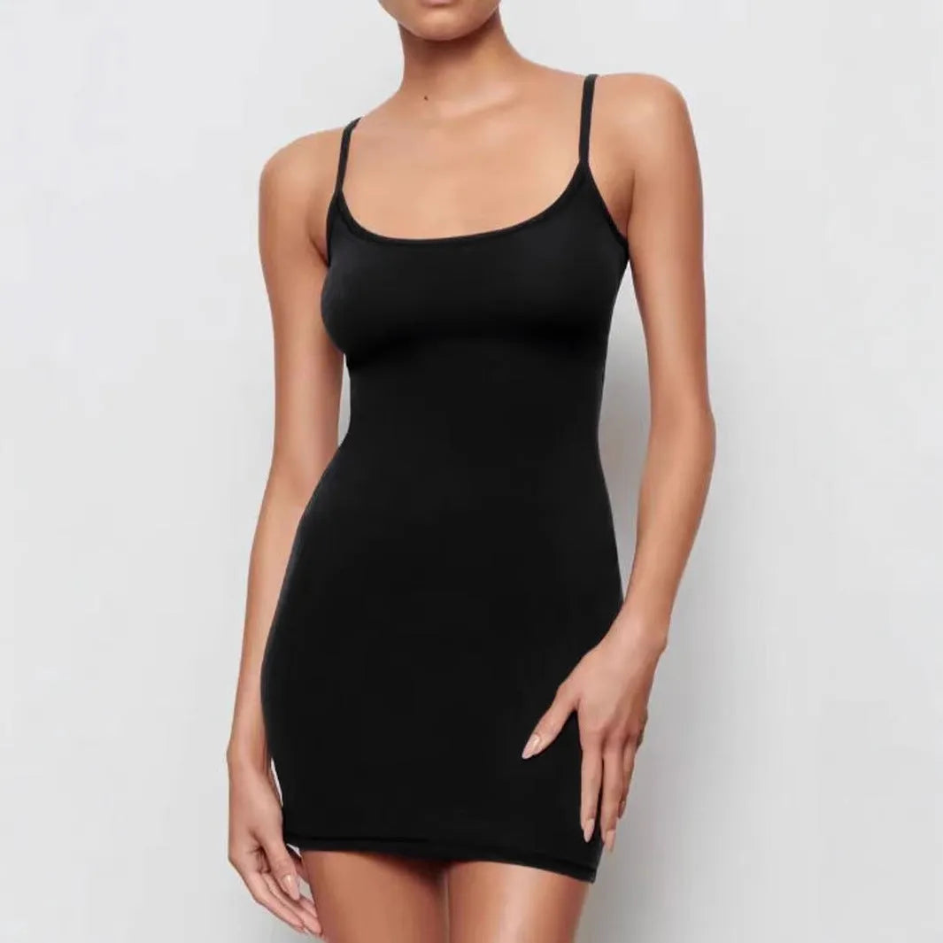 A black skinny sheath dress with a sling neckline and short mini length on a model.