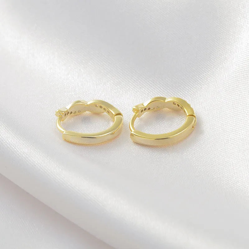Close-up of women's geometric ear clips with interwoven hemp rope centre in gold tone.
