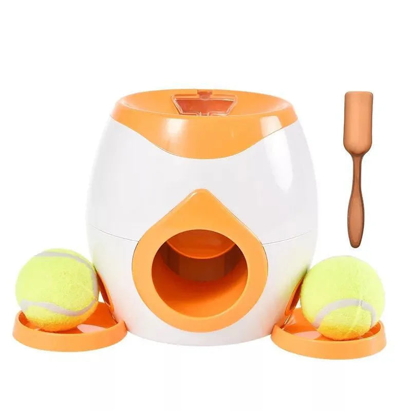 Smart pet feeder reward machine with two tennis balls and treat dispenser in green and white colour, shown on a wooden floor