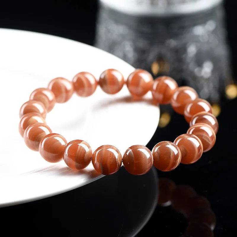 Natural Old Mine Rhodochrosite round bead bracelet with geometric design on wrist.