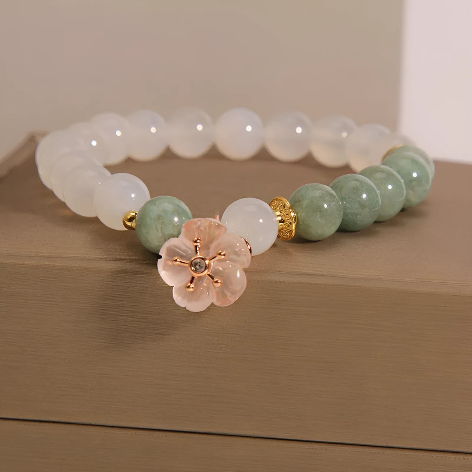 White agate jade bracelet with floral shape on a casual model wrist.