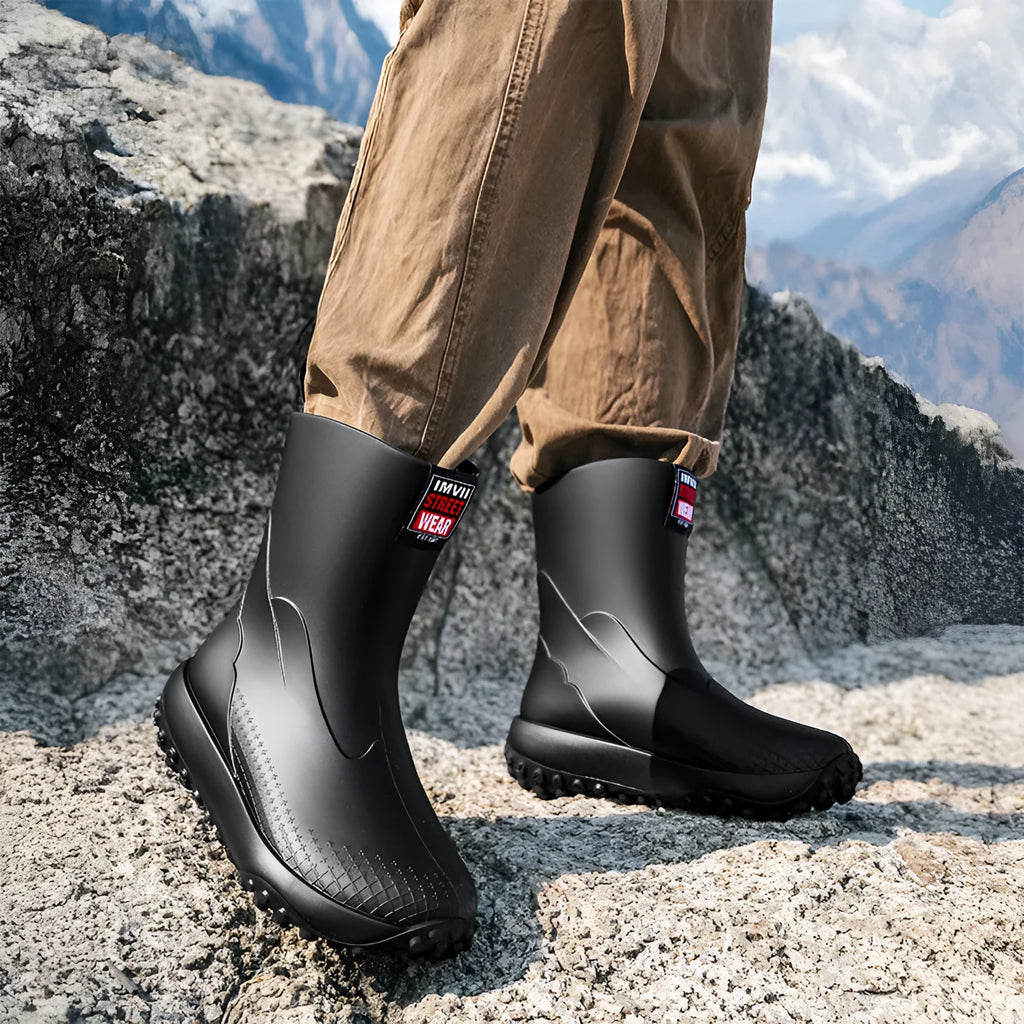 Men's black red PVC rain boot with round toe and plastic sole on a wet surface
