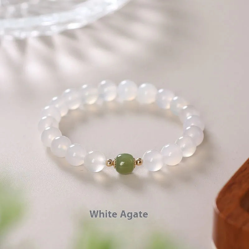 Handmade natural white agate and crystal bracelet with red cinnabar inlays on a wrist.