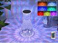 Vase-shaped transparent crystal bedside lamp with touch controls and LED lights on a table.