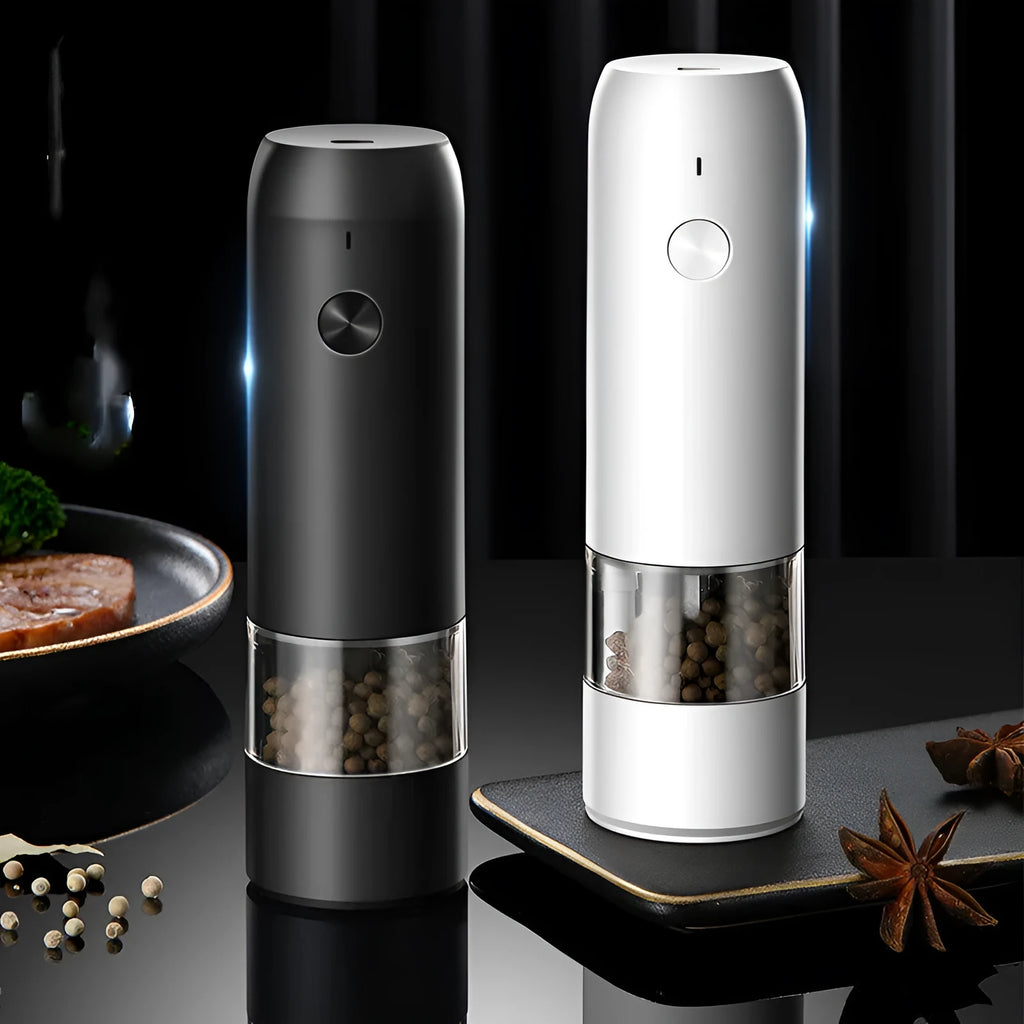 Black and silver electric pepper and salt grinder set with clear acrylic body on a kitchen counter.