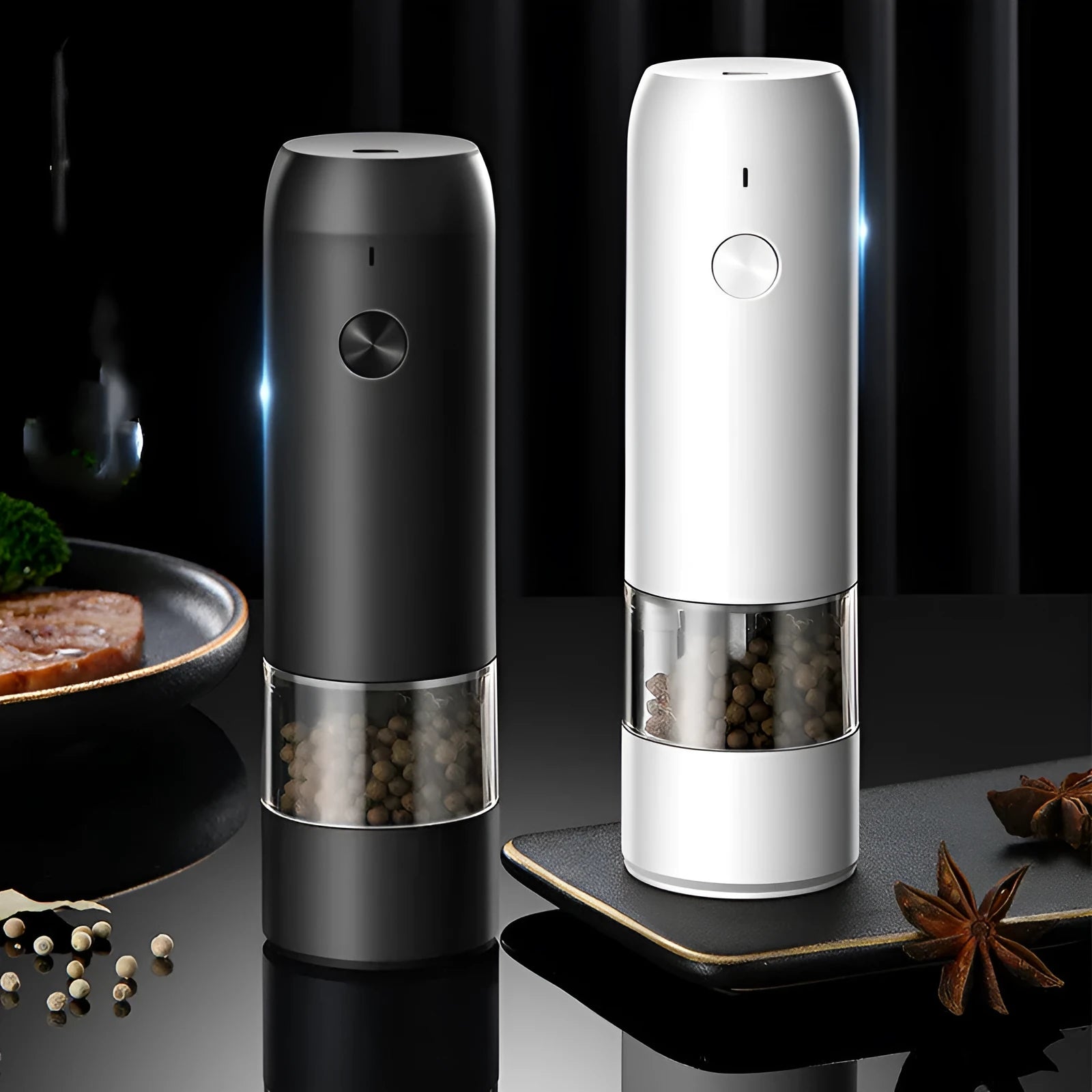Black and silver electric pepper and salt grinder set with clear acrylic body on a kitchen counter.