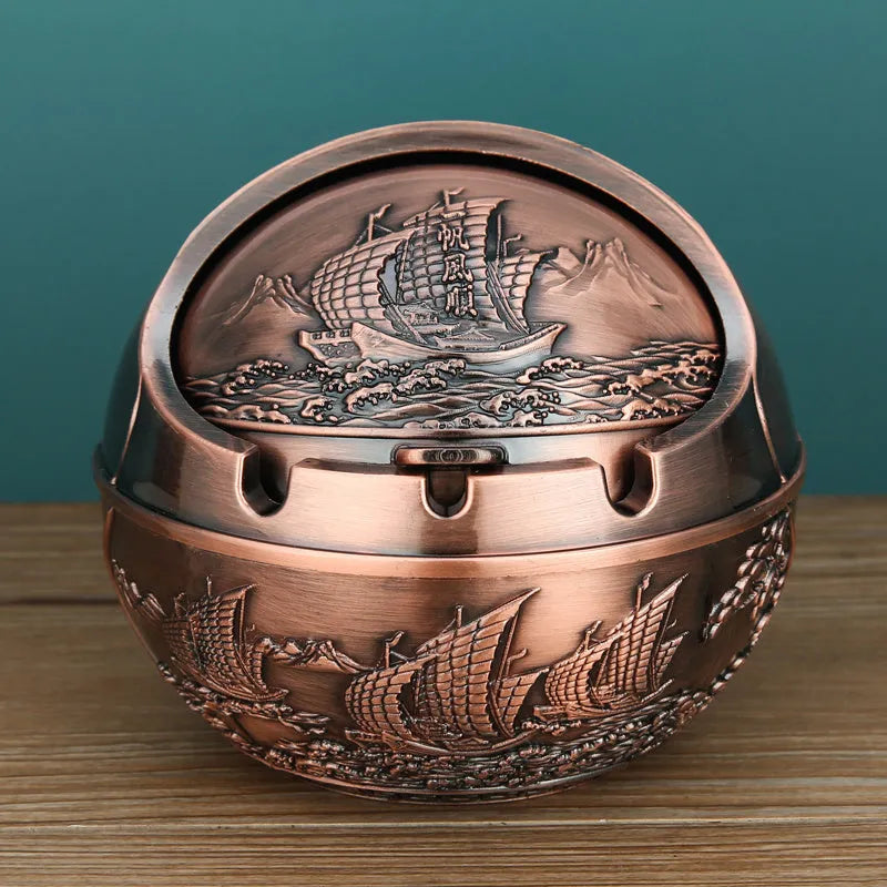 Bronze and red copper alloy decorative ashtray with smoke-extinguishing slot on a table.