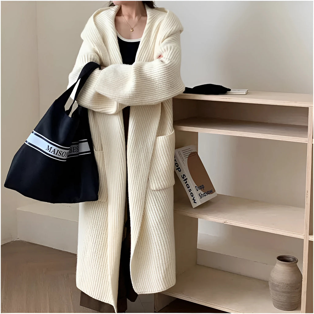 A woman wearing a long, loose, milky white hooded cardigan coat with raglan sleeves.