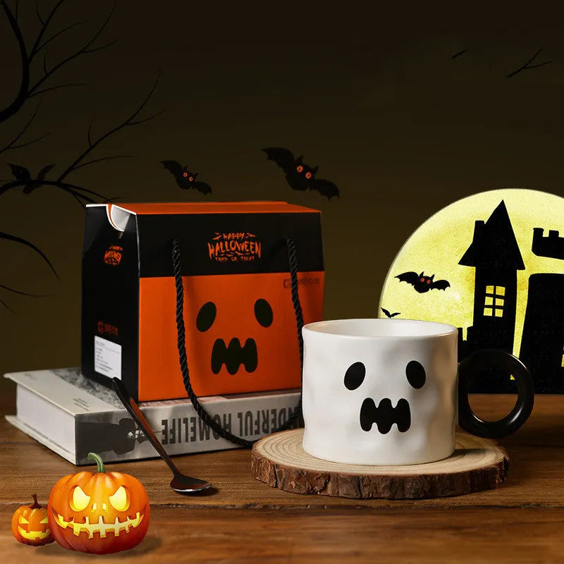 Orange ceramic Halloween pumpkin cup with handle beside dessert spoon in gift box