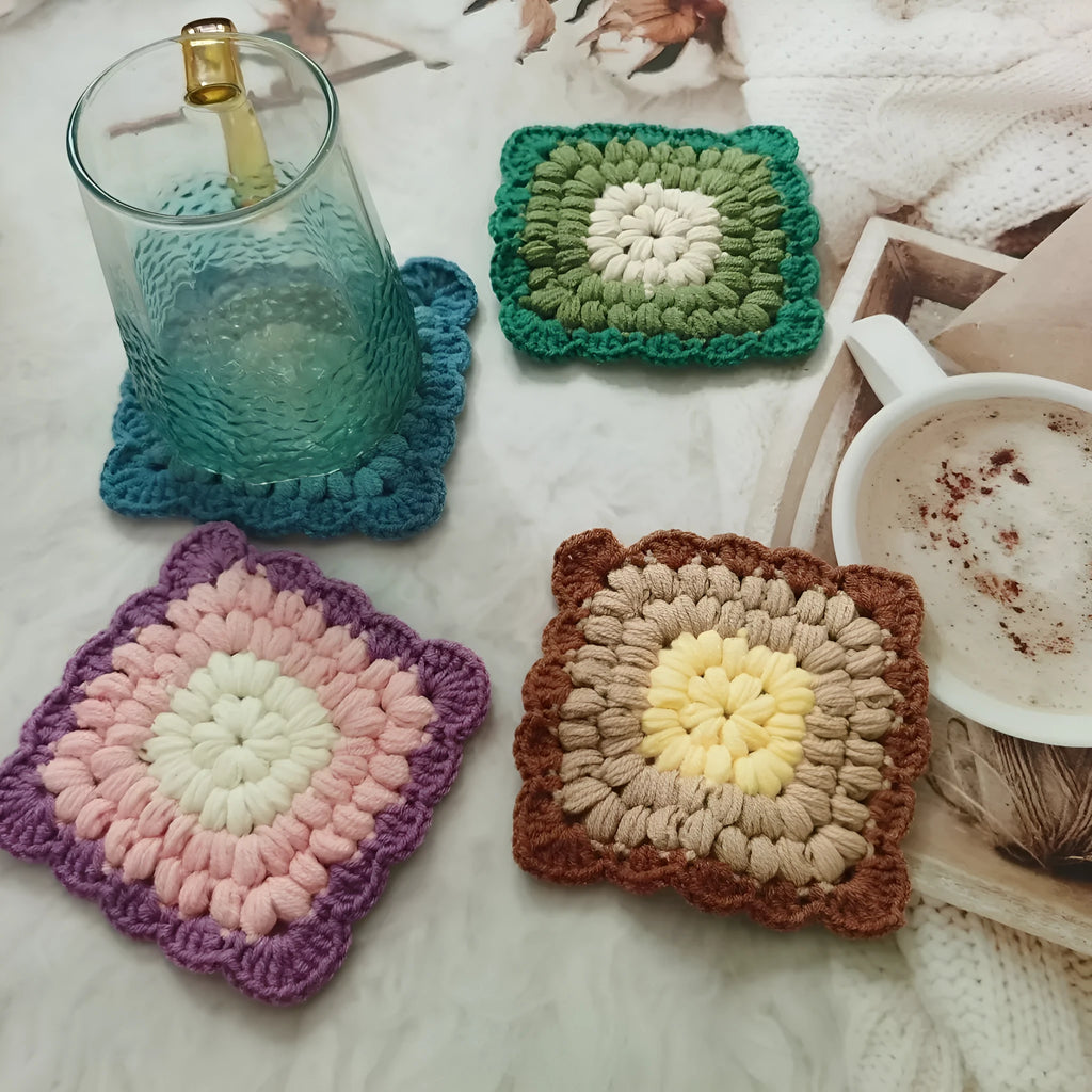 Square crocheted wool placemat with Grandmother Lattice pattern for cup heat protection.