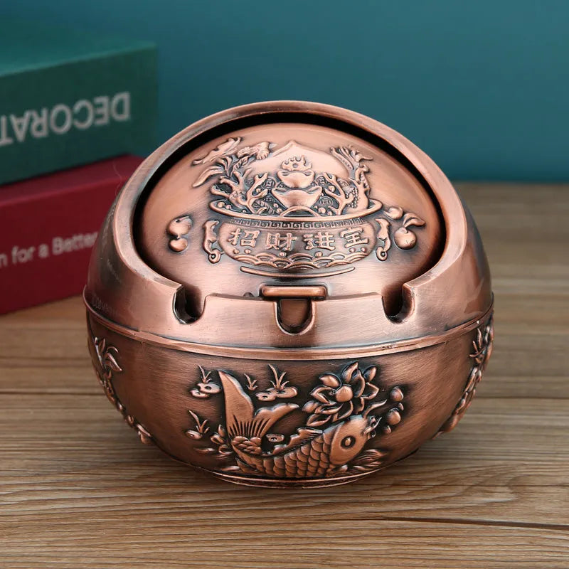 Bronze and red copper alloy decorative ashtray with smoke-extinguishing slot on a table.