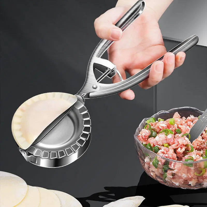 Silver-colour stainless steel manual dumpling mould on a kitchen counter.