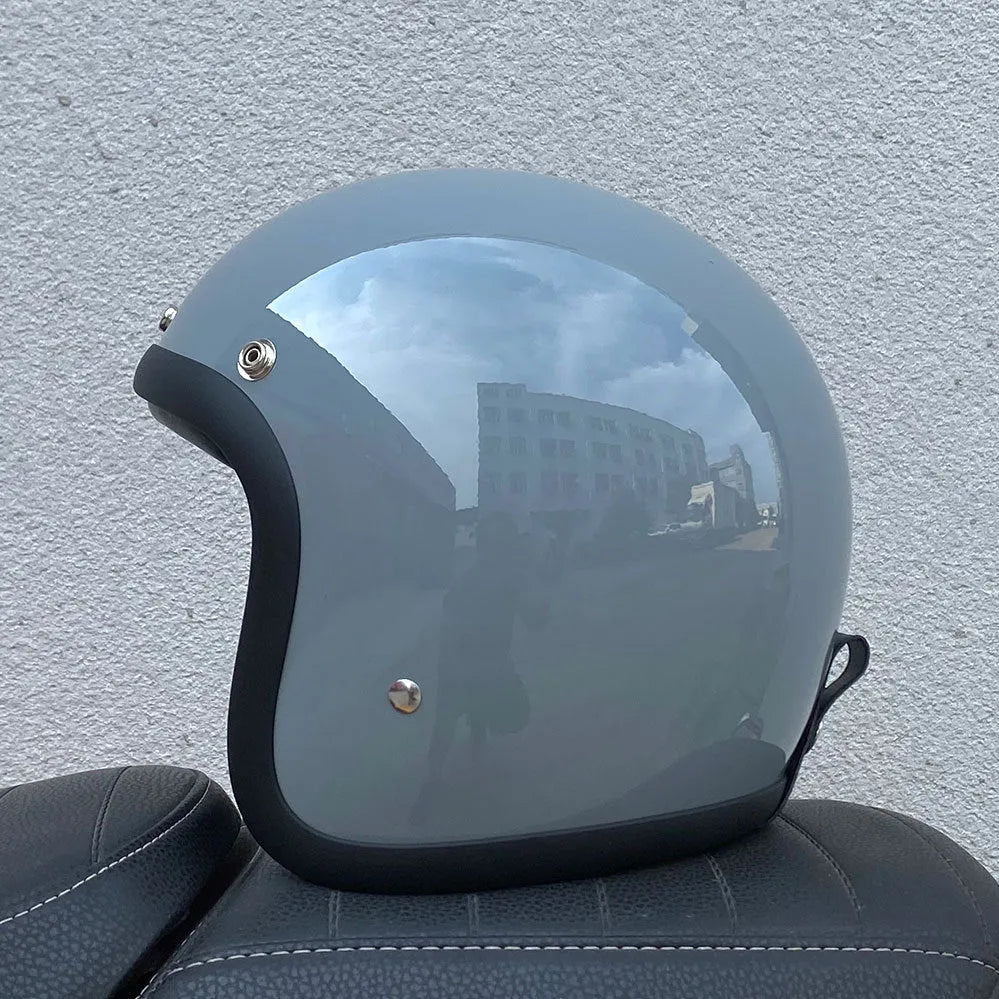 Retro-style open-face motorcycle half helmet in cement grey with a glossy FRP shell and quick-release chin strap.