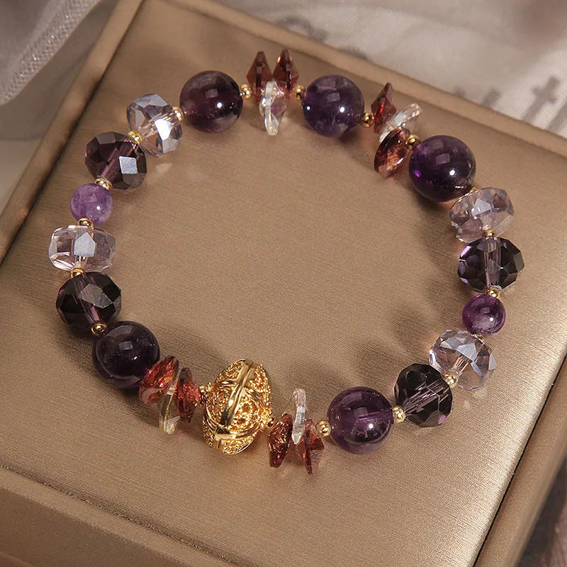 Purple crystal bracelet with pumpkin beads, wind chime charms, and rhinestone details on a wrist.