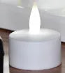 White plastic rechargeable LED candle lamp with yellow glowing flame on a table.