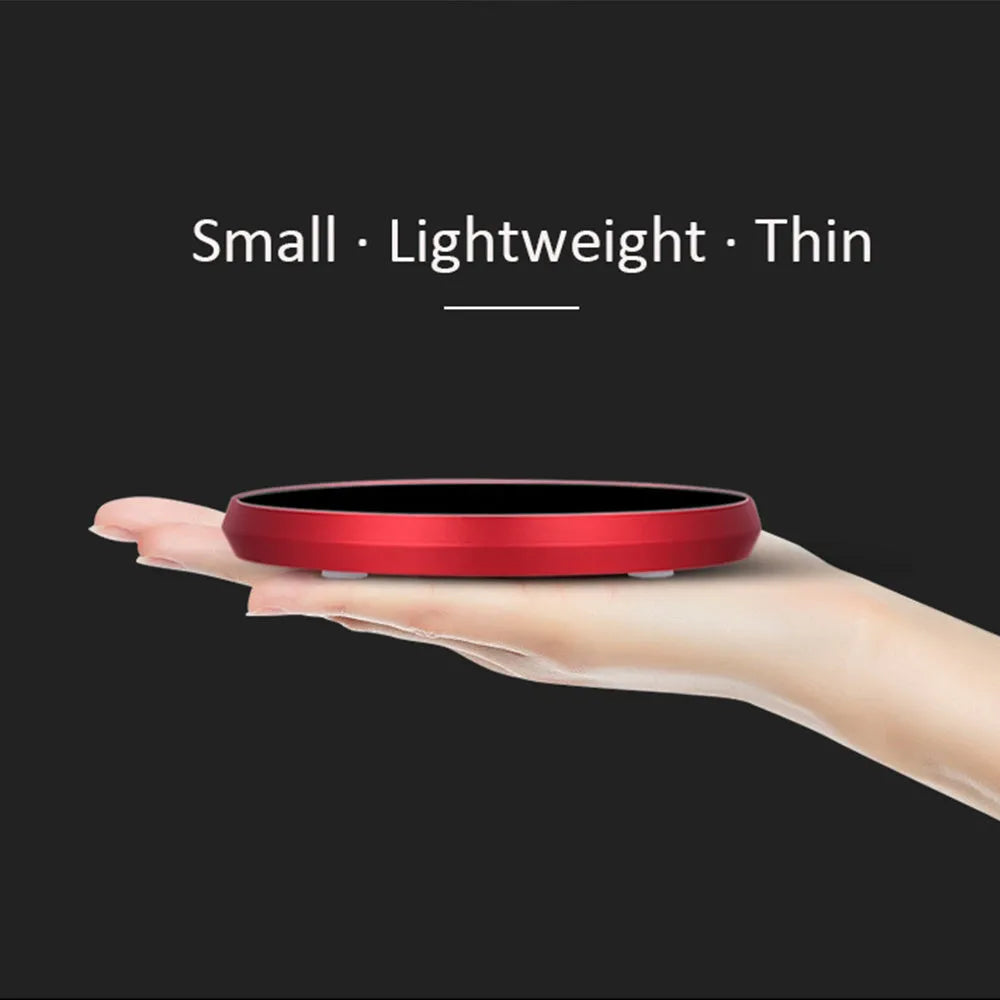 Black USB-powered beverage heating coaster with touch control and coloured LED lights on a wooden desk.