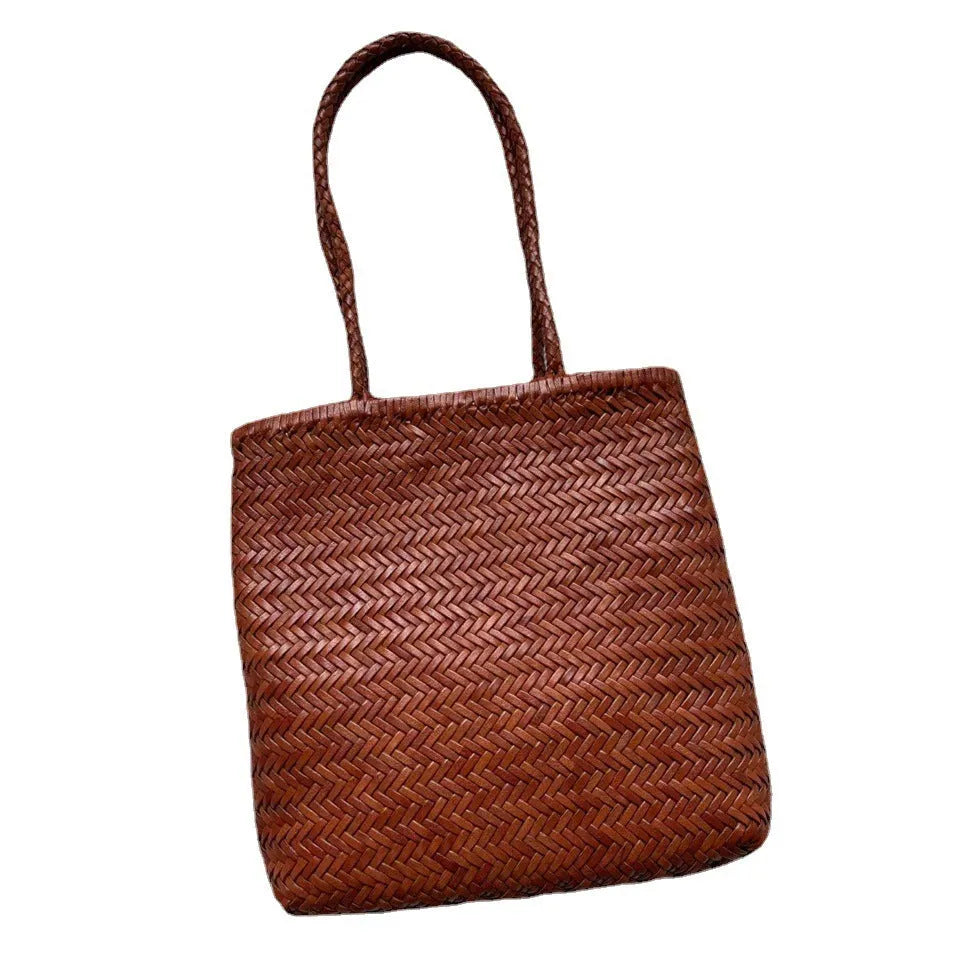 Brown handmade woven leather tote bag with a three-dimensional front pocket and shoulder strap.