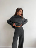 Women's dark grey acrylic sweater with side slits and matching full-length trousers laid flat.