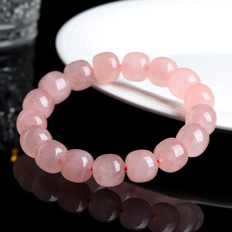 Natural pink crystal barrel bead bracelet with geometric design on a wrist.