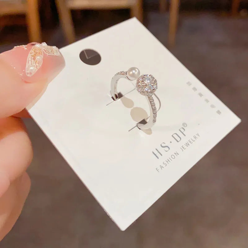 Golden open-end ring with round zircon stone on a white background.