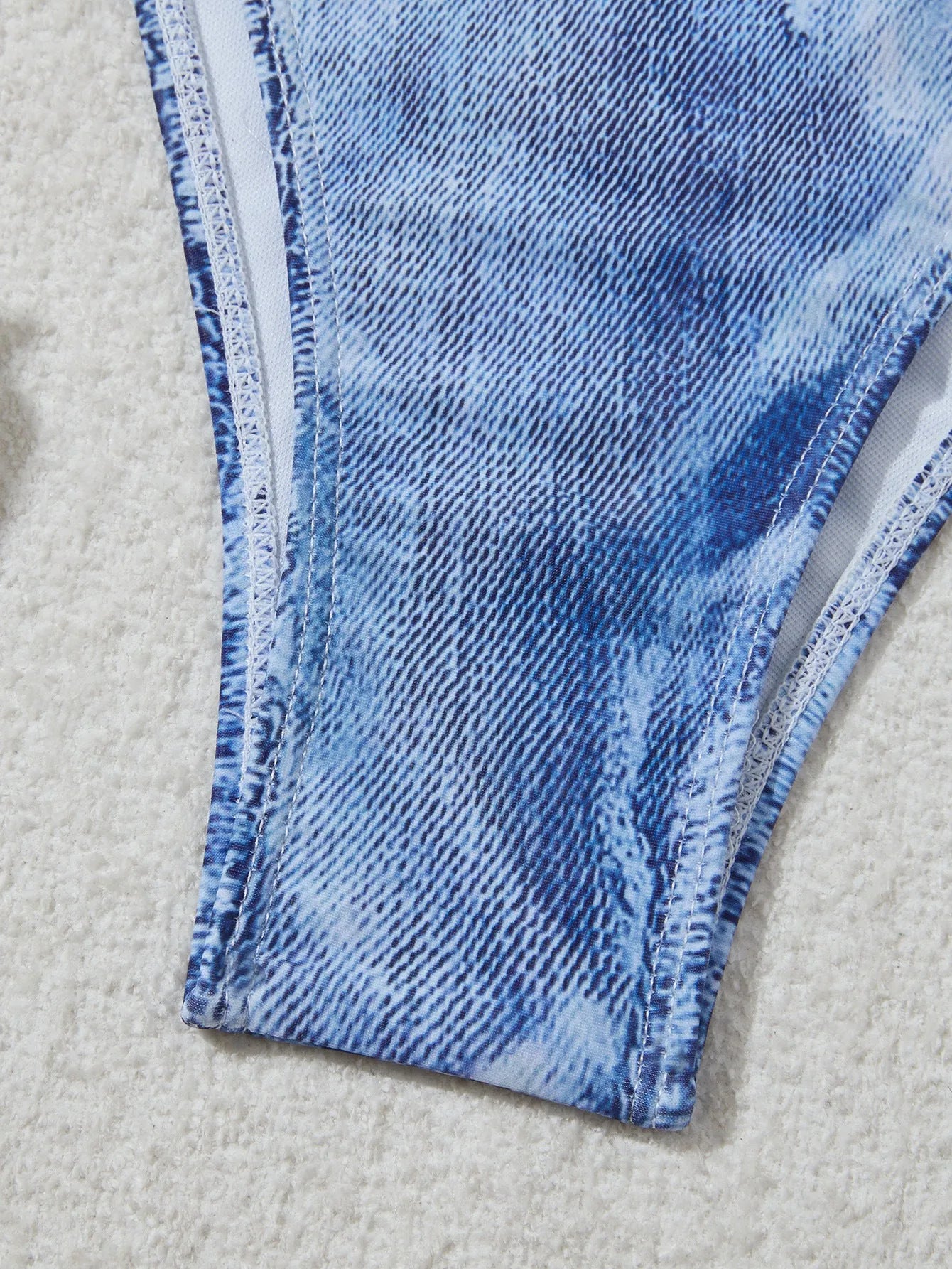 Denim blue printed women's two-piece bikini with thin straps, laid flat.