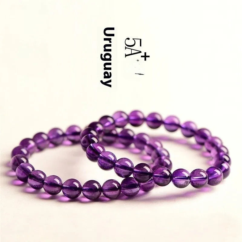 Close-up of a polished natural amethyst bead bracelet with a sliding knot closure on a wrist.