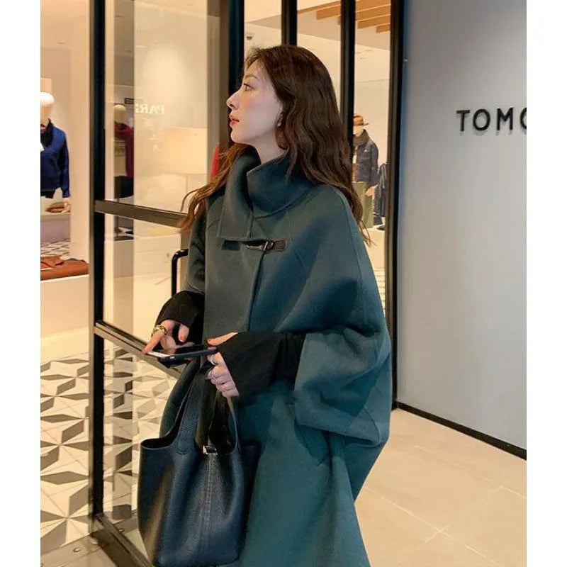 Women's green Korean-style lengthened coat with flight sleeves on a hanger