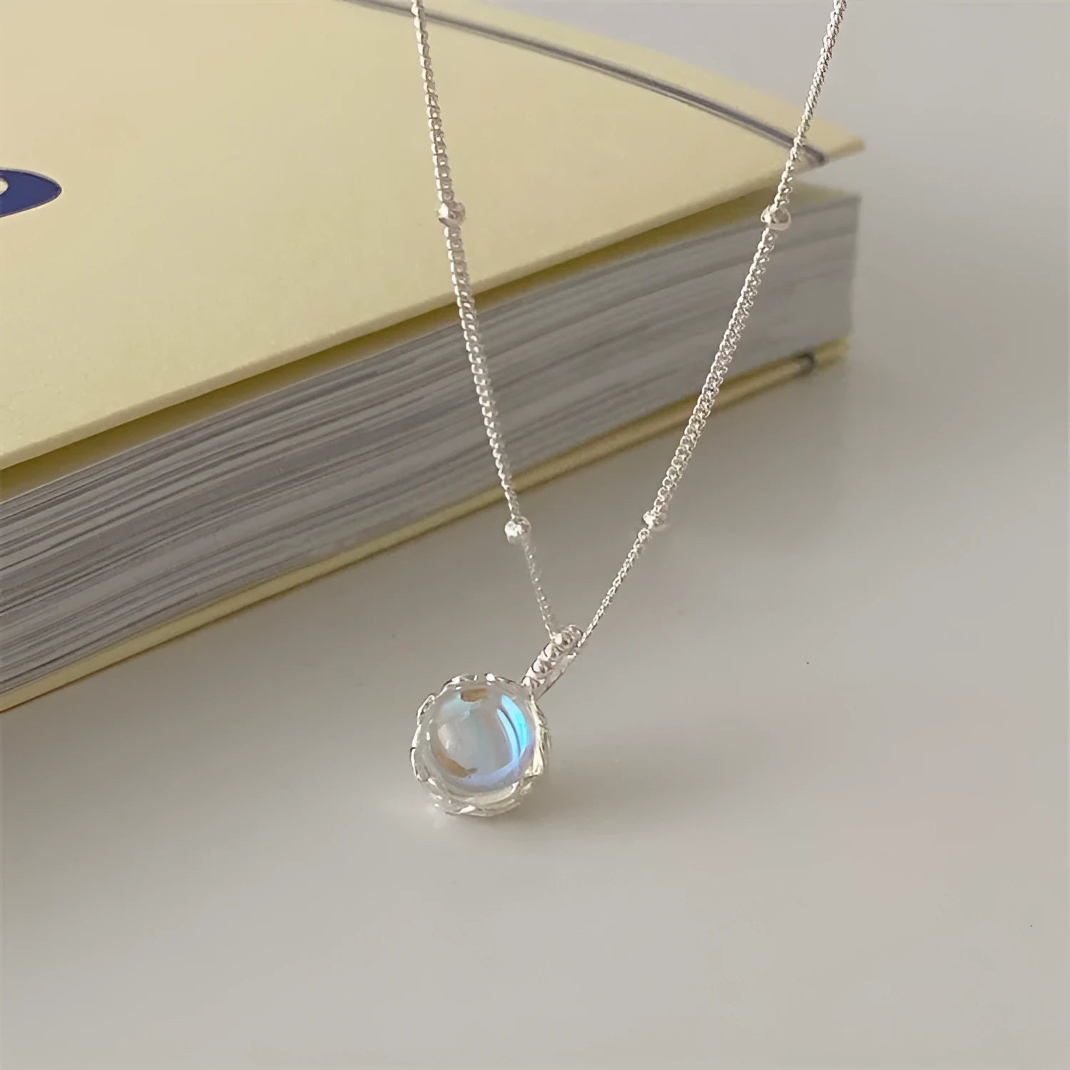 Silver geometric stone necklace on a curb chain, showing adjustable length and polished pendant.