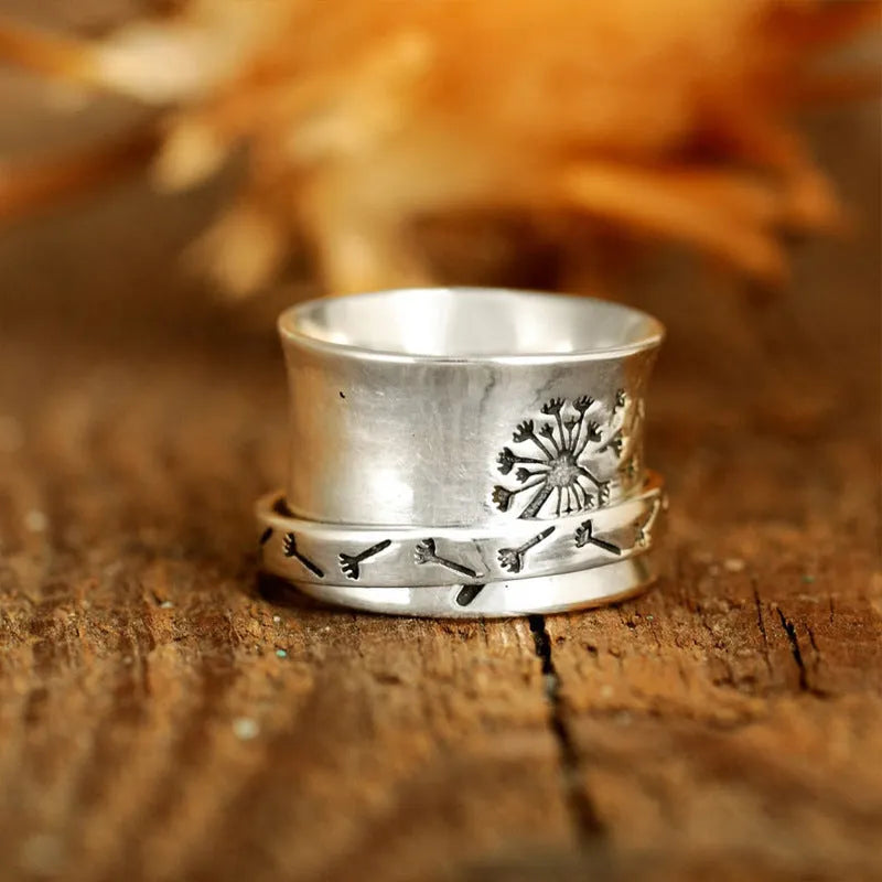 Silver-coloured rotatable flower fashion ring on a finger, showing the floral detail.