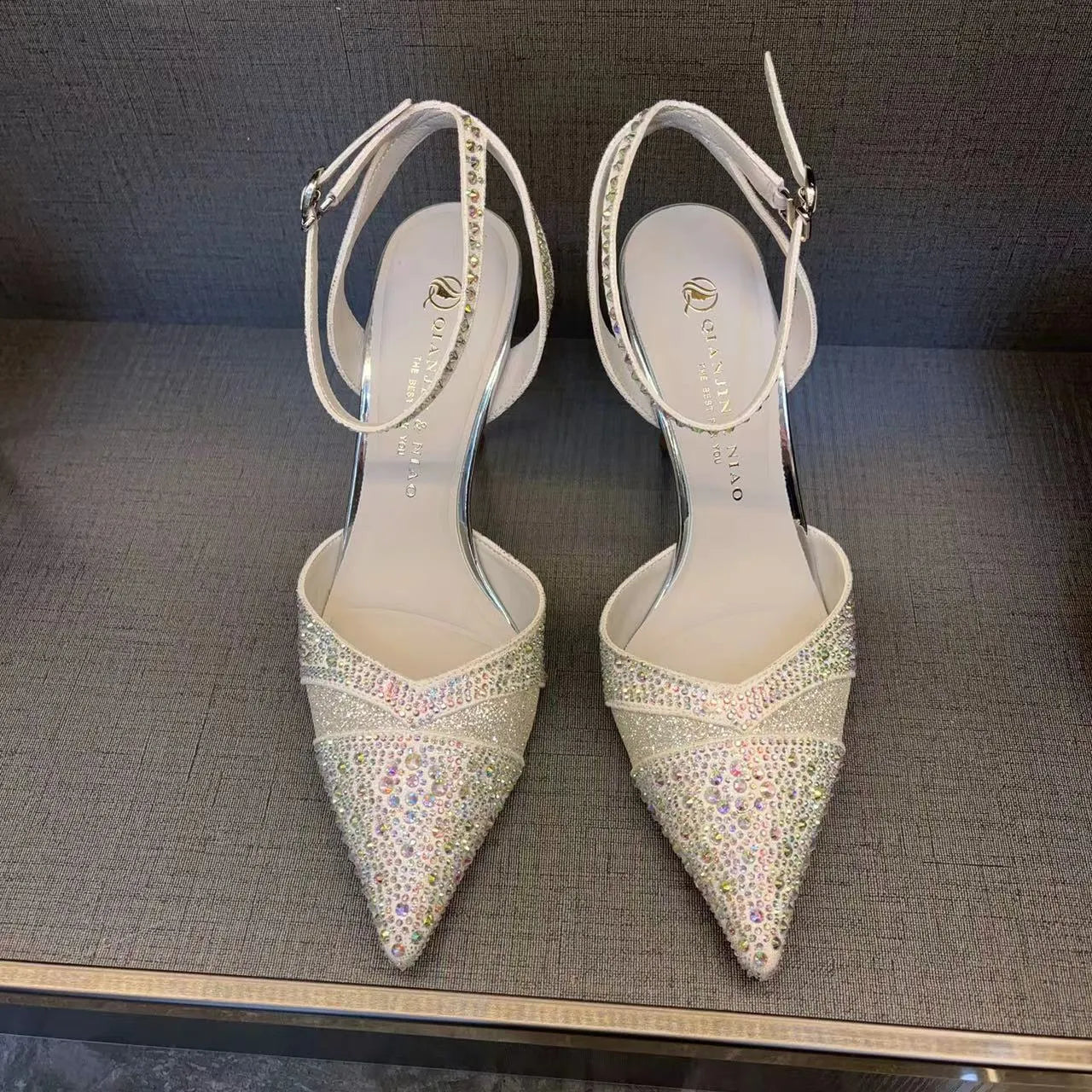 Women's silver hollow high heels with red sole and pointed stiletto heel.