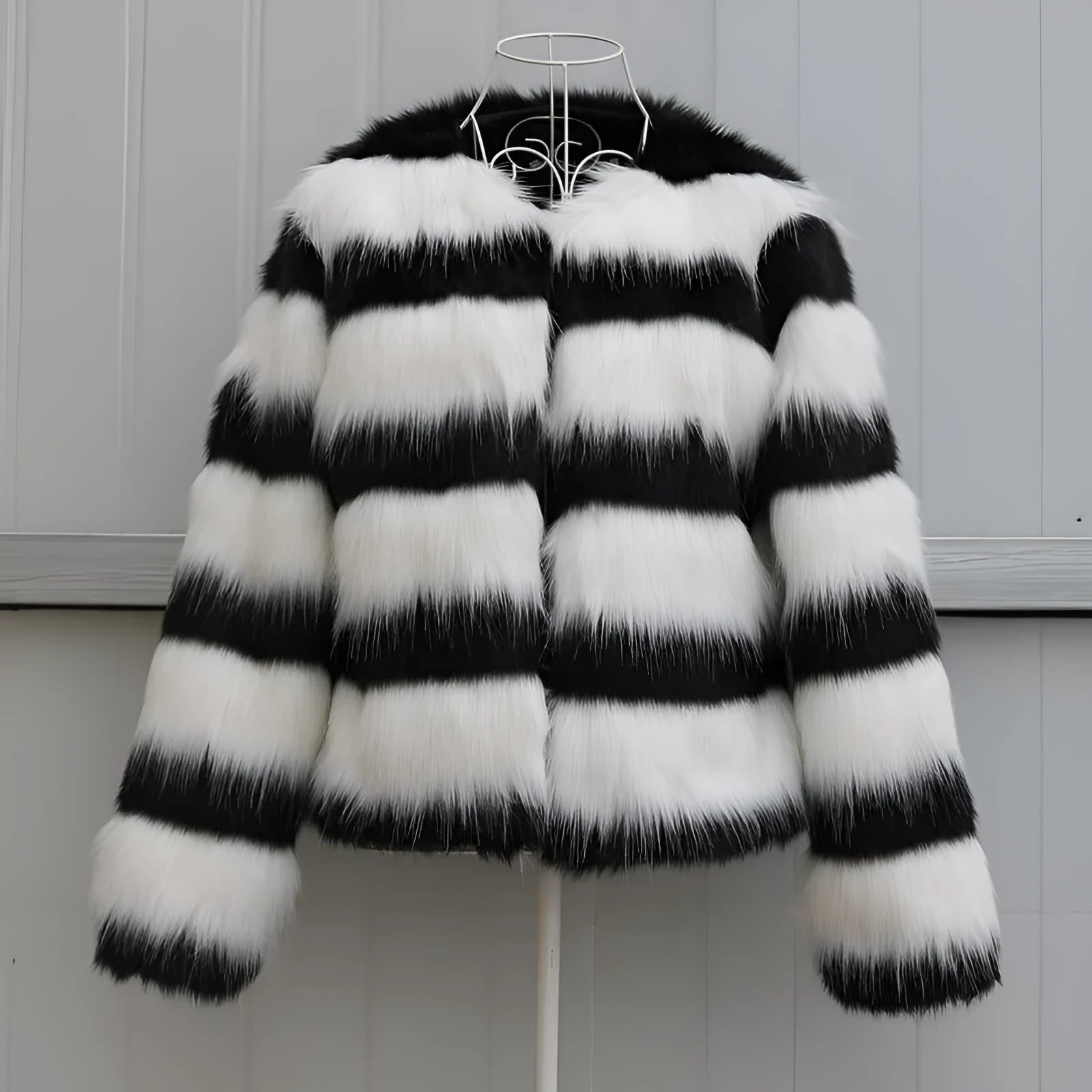 Women's long-sleeved black and white striped faux fur leather jacket on a hanger.