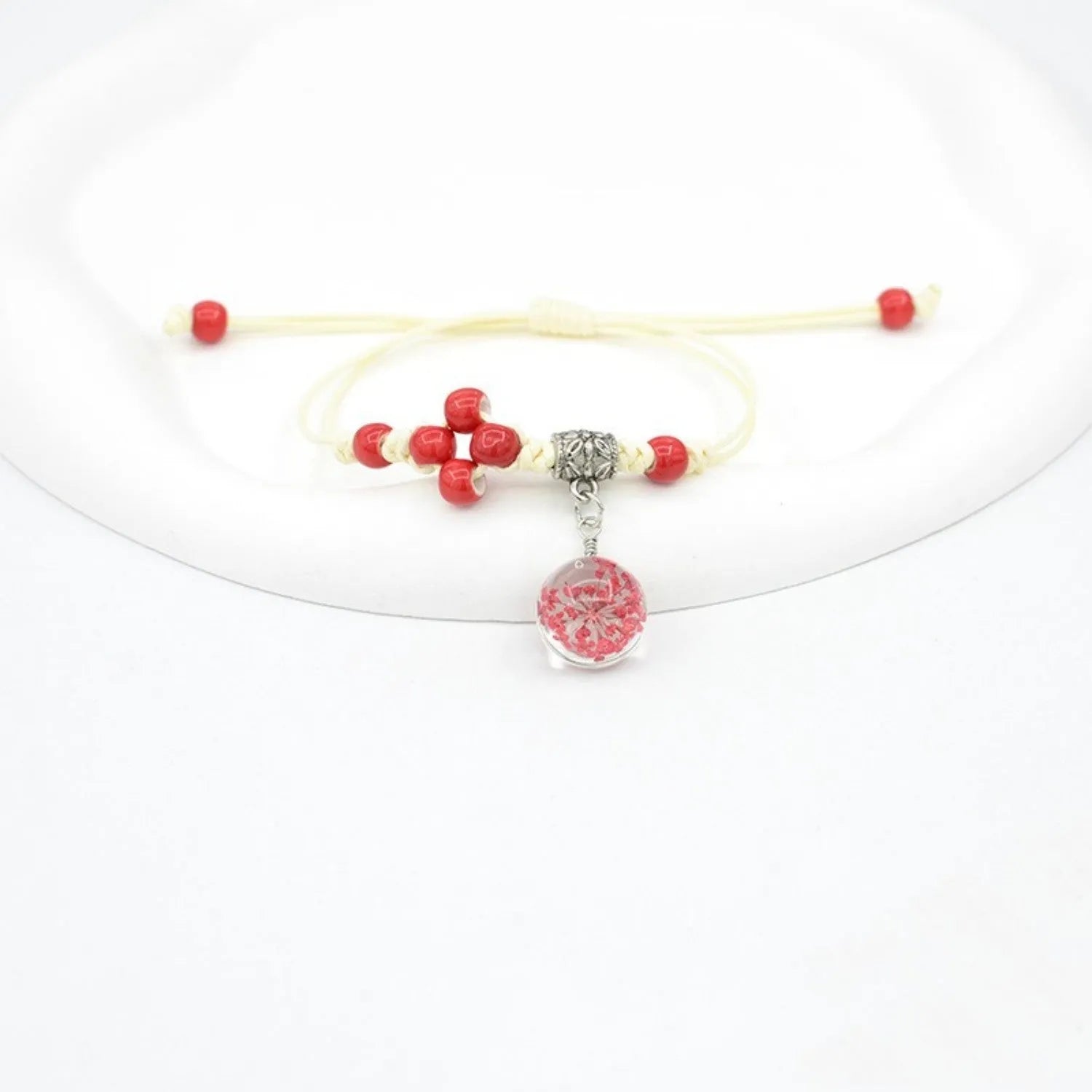 Close-up of a hand-woven glass bracelet with large 1.4cm beads containing real dried flowers and lace floral detailing.