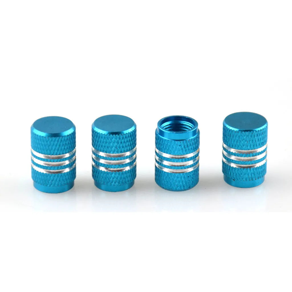 Set of coloured aluminium alloy tyre valve caps for car wheels on a grey background.