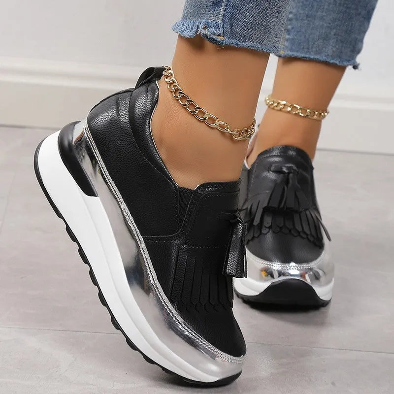 Women's black casual platform shoes with a tassel detail and a distinctive muffin-style wedge heel.