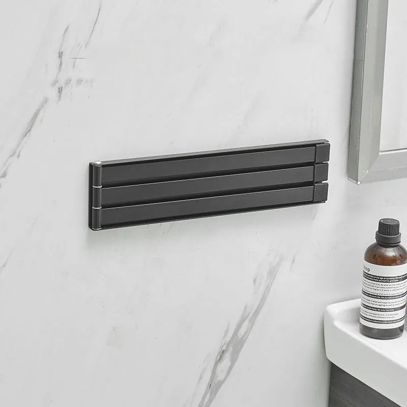 Nordic style black folding towel rack mounted on a bathroom wall with non-perforated installation.
