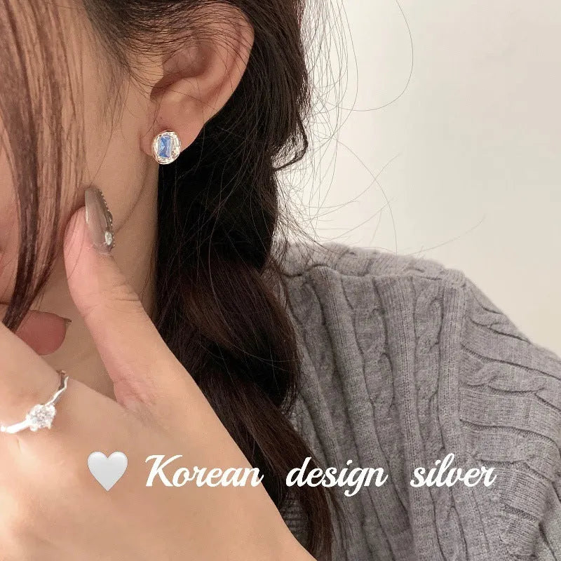 Silver geometric earrings with oval blue diamond wrapped in heart motif